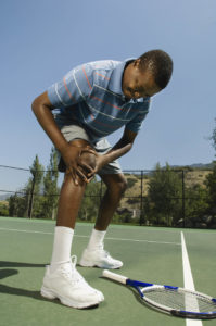 Tennis player holding injured knee